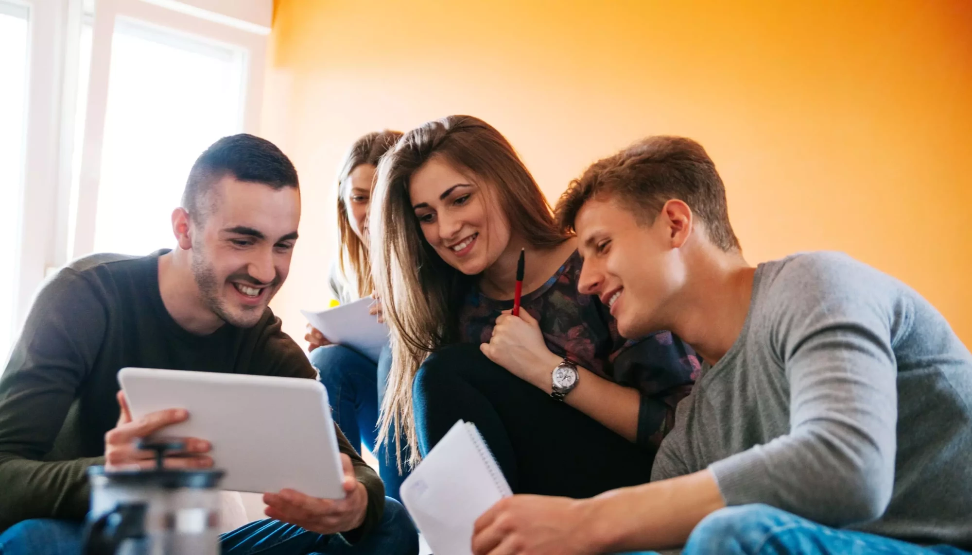 Étudiants en formation à Toulouse travaillant ensemble sur une tablette et des notes dans un cadre convivial.